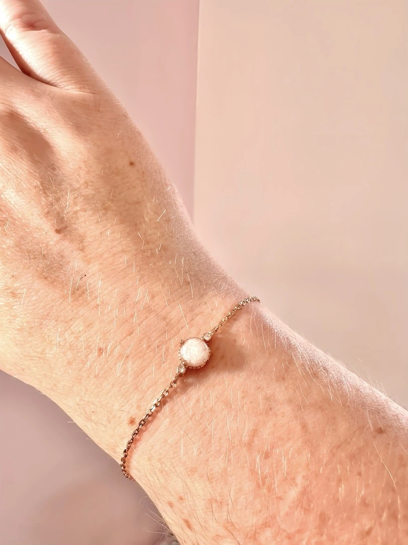 Draagfoto van de armband in rosé kleur gevuld met witte assen